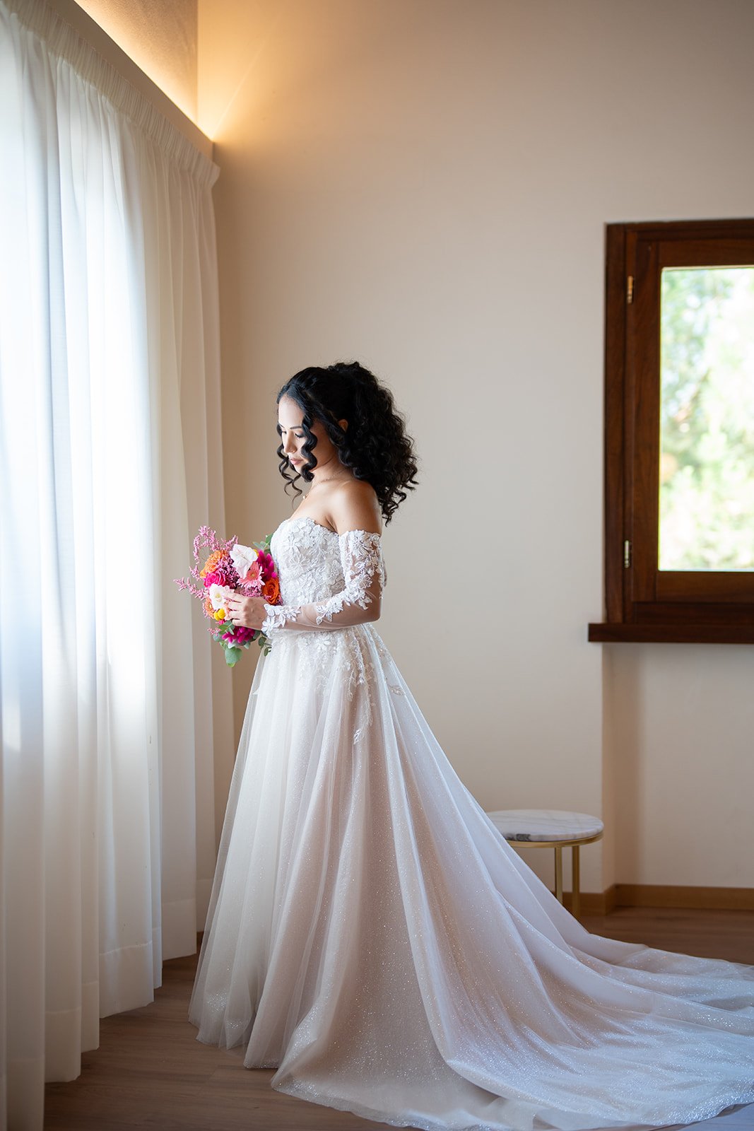Bride by a sunlit villa window